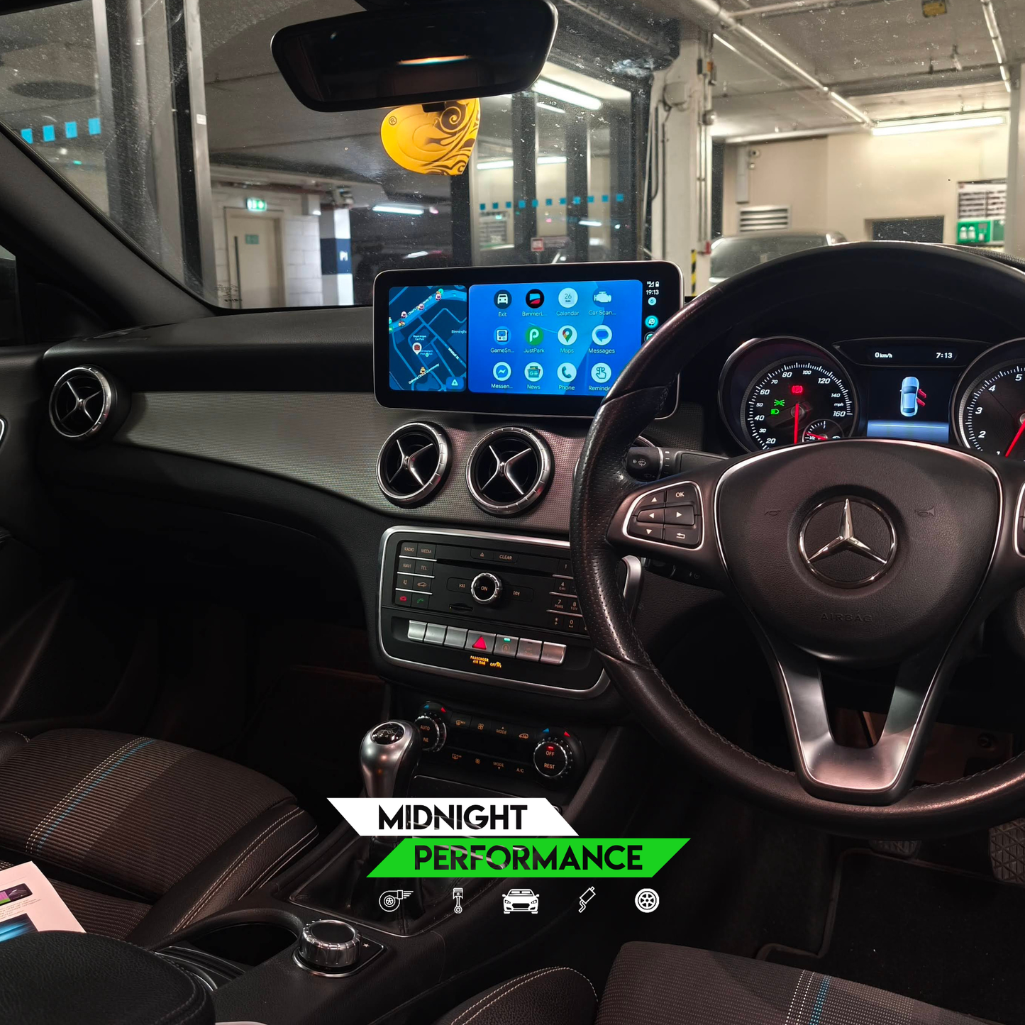 Car interior with dashboard display and steering wheel, featuring Mercedes-Benz logo.