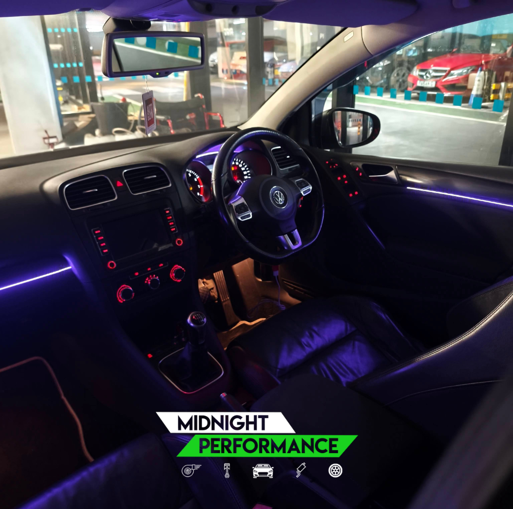 Car interior with neon lights and 'Midnight Performance' branding.