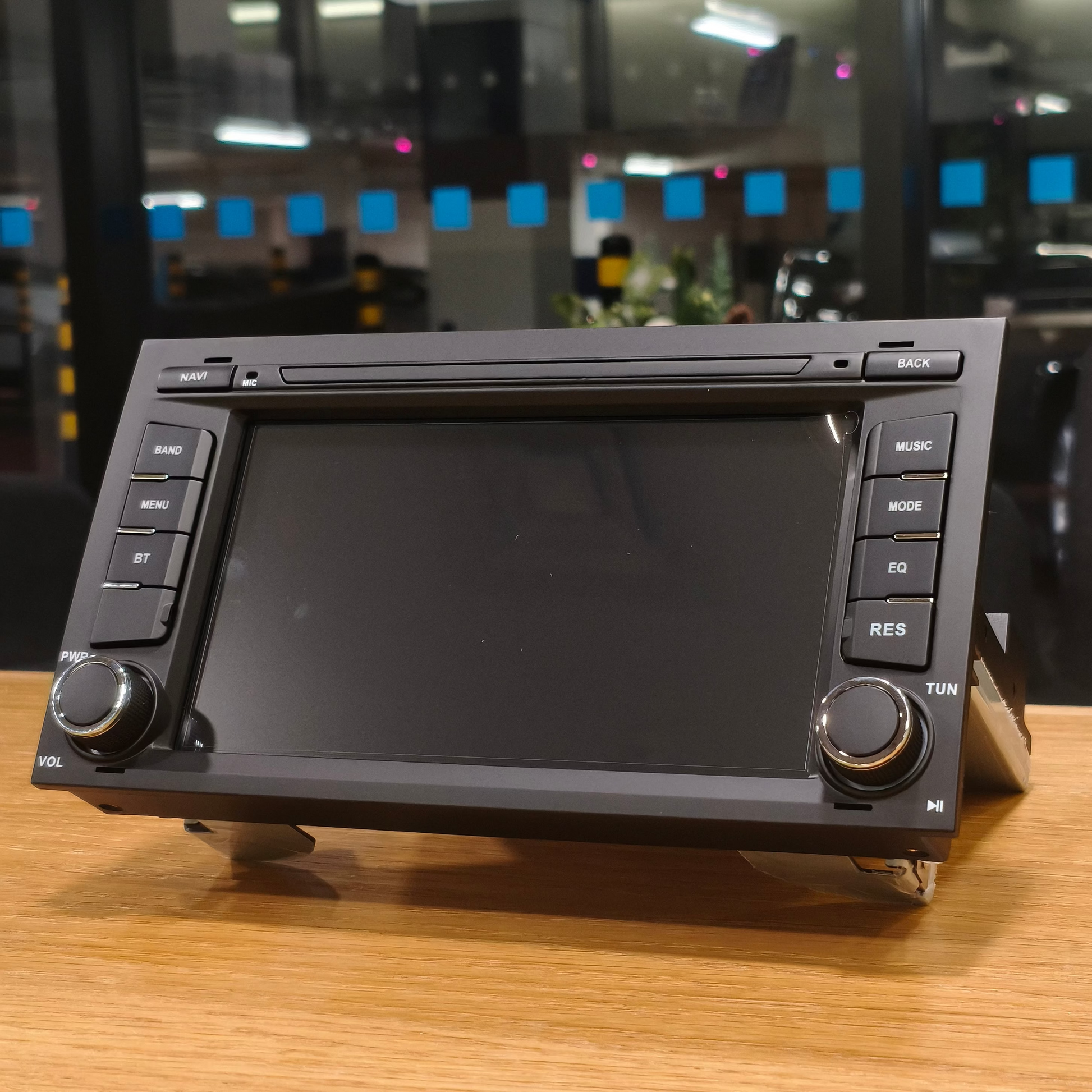 Car stereo system on a wooden surface with a blurred indoor background