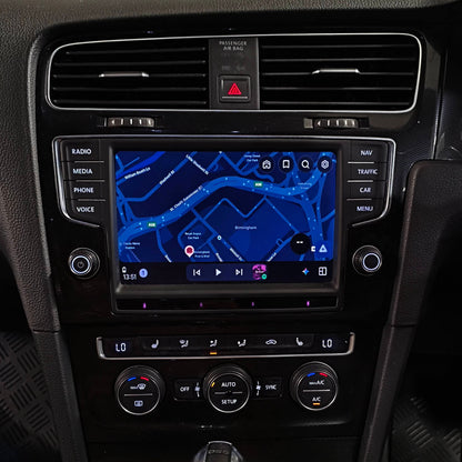 A car's center console featuring a large touchscreen infotainment system with a blue navigation map, climate control dials, and a gear shifter.